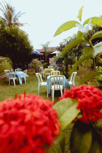 a group of tables and white chairs and red flowers at RECANTO JK in Taguatinga