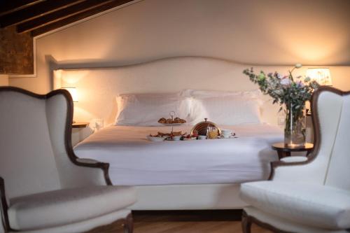 a bedroom with a white bed with two chairs at Le Ali Del Frassino in Peschiera del Garda