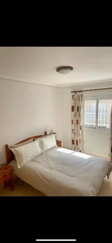 a bedroom with a white bed and a window at 2 bedroom Duplex Apartment Playa Flamenca in Orihuela Costa