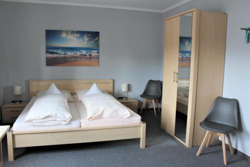 a bedroom with a bed with two chairs and a mirror at Hotel Schlömer in Cloppenburg