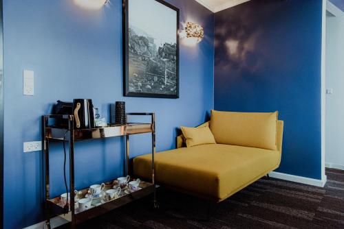 a living room with a yellow couch and a blue wall at Hotel Hafnia in Tórshavn