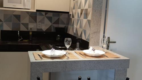a kitchen counter with two plates and glasses of wine at Apartamento Mania in Vitória