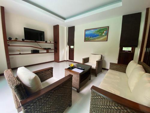a living room with a couch and chairs and a television at T-Villa Phuket Nai Yang Beach in Nai Yang Beach