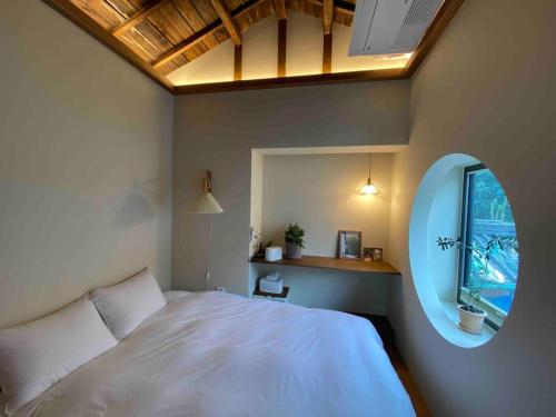 a bedroom with a white bed and a round window at Jongno Haru in Seoul