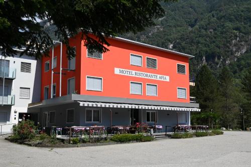 a building with tables and chairs in front of it at Motel Afia in Cama