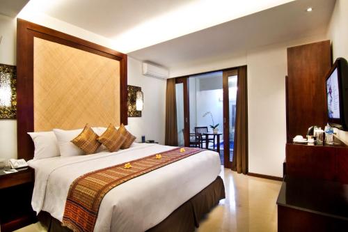 a hotel room with a large bed and a television at Best Western Kuta Villa in Kuta