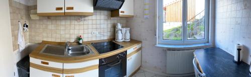 una pequeña cocina con fregadero y ventana en Schwarzwald - Gemuetliches 2 Zimmer Apartment! en Dunningen