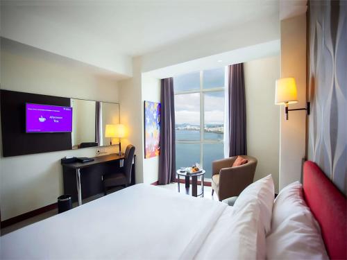 a hotel room with a large bed and a television at Best Western The Lagoon Hotel in Manado