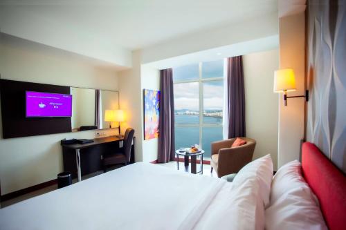 a hotel room with a large bed and a television at Best Western The Lagoon Hotel in Manado