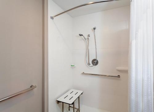 a white bathroom with a shower and a bench at Holiday Inn - Tallahassee E Capitol - Univ by IHG in Tallahassee