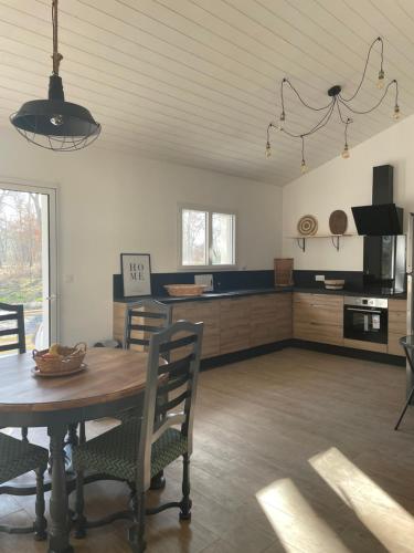 une cuisine et une salle à manger avec une table et des chaises dans l'établissement Maison neuve entre Bassin d'Arcachon et Landes, à Le Muret