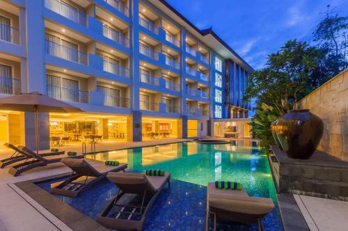 a hotel swimming pool with chairs and a hotel at Best Western Kamala Jimbaran in Jimbaran
