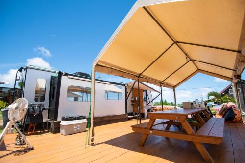 awning over a deck with a picnic table and a trailer at ペットOK! JUNGLIA 15分! サウナ-プール-Private Villa 405 in Nakijin