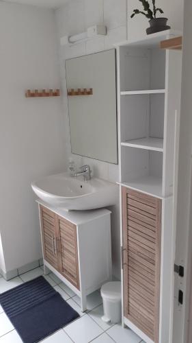 Baño blanco con lavabo y espejo en L'APPART DU RIS, en Douarnenez