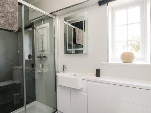 a white bathroom with a sink and a shower at Stables Cottage in Langholm