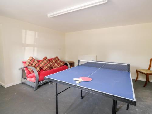 a ping pong table in a room with a couch at Stables Cottage in Langholm