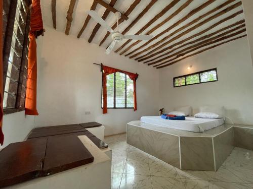 - une chambre avec un lit et un ventilateur de plafond dans l'établissement Botanica Eco Lodge, à Michamvi