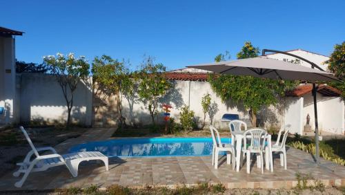 a group of chairs and an umbrella next to a pool at Chalés Villa Carpe Diem in Bezerros