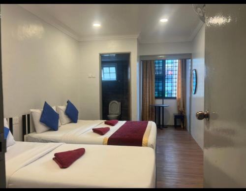 a hotel room with two beds and a door at ESM Hotel in Tanah Rata