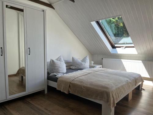 1 dormitorio con cama con almohadas y ventana en Saechsische-Schweiz-Ferienhaus-Wohnung-1-mit-Elbblick-Sauna-und-Kamin, en Königstein