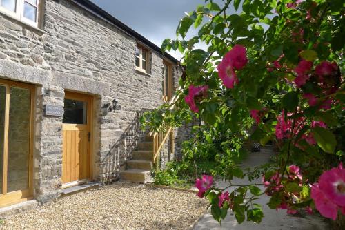 a stone house with pink flowers in front of it at Tuell Farm Cottages in Tavistock
