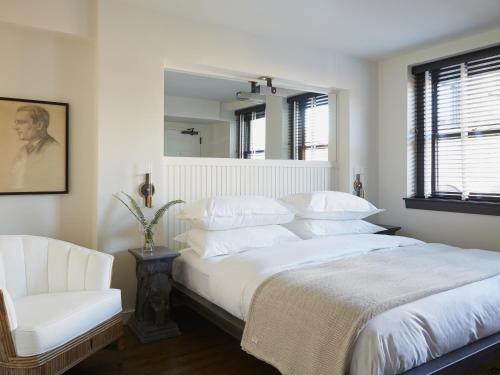 Un dormitorio con una cama blanca y una silla blanca. en Neptune, an Ash Hotel, en Providence