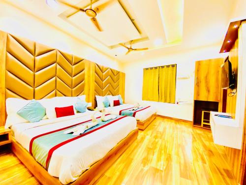 two beds in a room with wooden floors at Avista Hotel in Amritsar