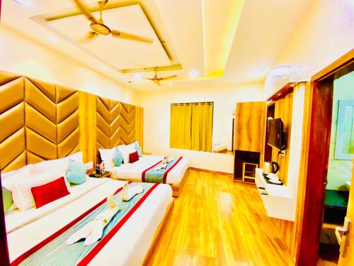 a hotel room with two beds and a television at Avista Hotel in Amritsar