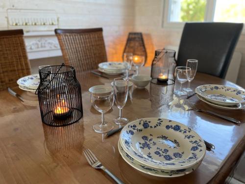 - une table en bois avec des assiettes et des verres à vin dans l'établissement Maison familiale et cosy, à Roscanvel