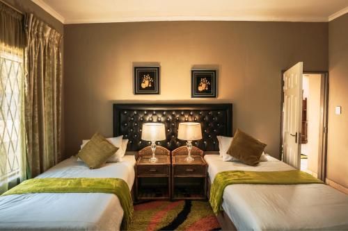 duas camas num quarto com duas lâmpadas em Ramandire B&B em Witbank