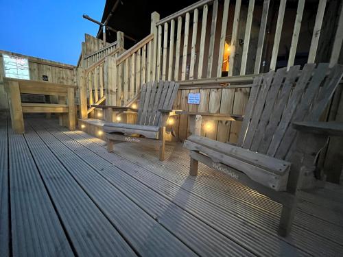 zwei Holzstühle auf einer Terrasse mit Lichtern in der Unterkunft Aladdin Safari Tent in Tenby