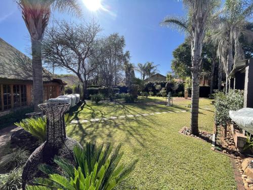 Un patio con palmeras y una casa. en @Grace Guesthouse, en Klerksdorp