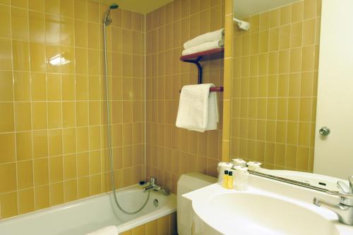 a bathroom with a sink and a toilet and a tub at New Hotel Saint Lazare in Paris