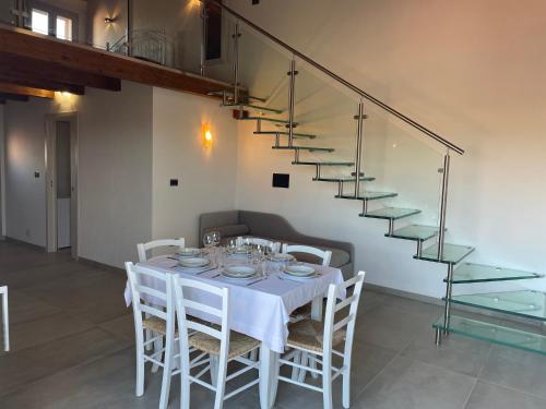 un comedor con una mesa con sillas blancas y una escalera en Villa Infinity, en Tergu