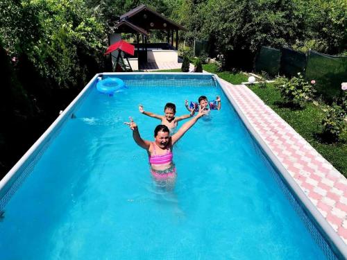 a man and two children in a swimming pool at Casa David Comarnic in Comarnic