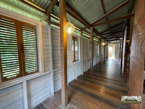 an empty porch of a house with wooden floors and windows at Paganakan Dii Tropical Retreat in Sepilok