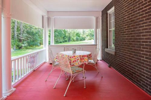 - une table et des chaises sur une terrasse couverte avec une fenêtre dans l'établissement The Manor at Glen Jean Meadows, 