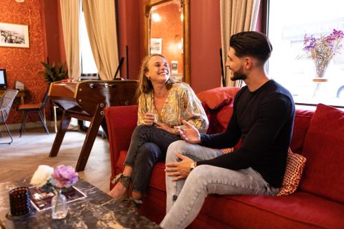a man and a woman sitting on a couch at Hotel Le Grimaldi by Happyculture in Nice