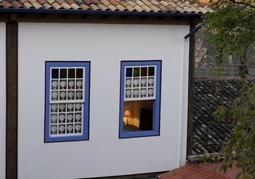 two windows on the side of a white building at Pouso da Chica in Diamantina