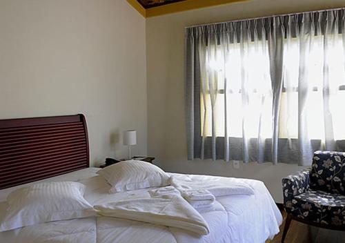a bedroom with a bed and a chair and a window at Pouso da Chica in Diamantina