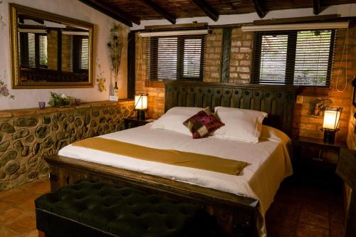 1 dormitorio con cama y banco. en Posada la Serena, en Villa de Leyva