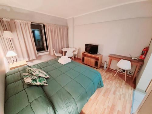 1 dormitorio con 1 cama verde y TV en Center 208 - DAT (Habilitación 170/2018), en San Carlos de Bariloche