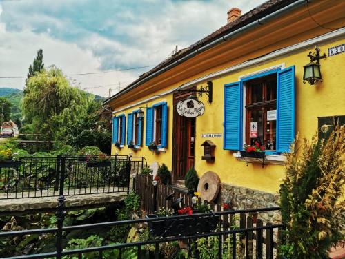 a yellow and blue building with blue shutters at Casa Borcean 2 in Sasca Montană