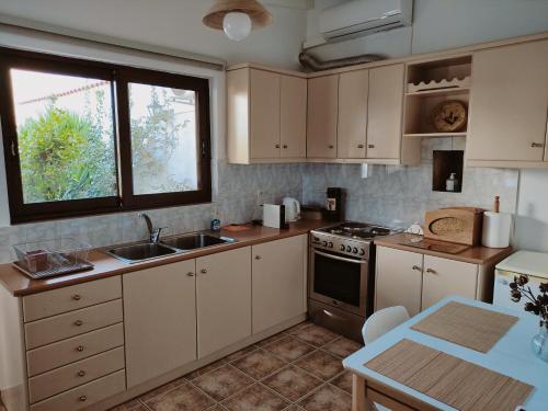 a kitchen with white cabinets and a sink and a stove at Cozy apartment in Peania (near Airport) in Paianía