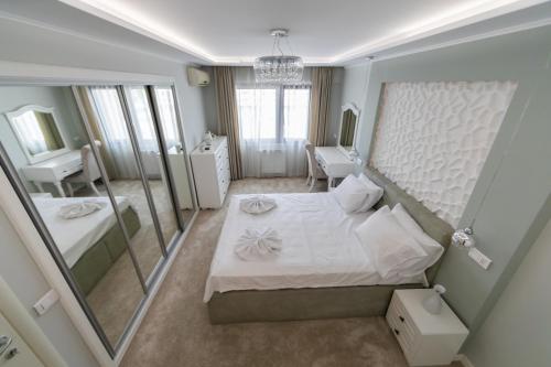 una camera da letto con un grande letto bianco e uno specchio di Saphir Stein Residence Apartment 19th a Bucarest