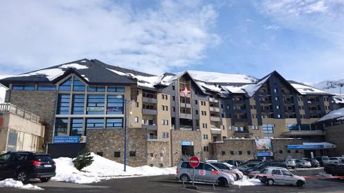 un gran edificio con coches estacionados en un estacionamiento en Le Cosy Pyrénées pied de pistes Sérias, en Germ