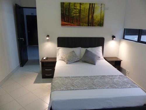 a bedroom with a large bed with two nightstands and a painting at Campo Godoy in Doradal