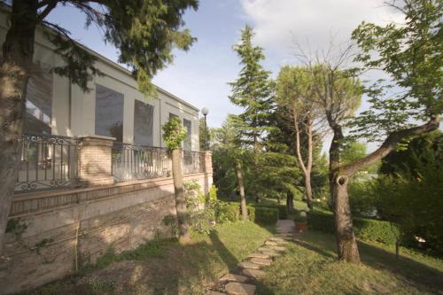 a house with a stone fence and a tree at Marchese Del Grillo in Fabriano
