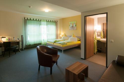 une chambre d'hôtel avec un lit et une chaise dans l'établissement Park-Hotel Leimen, à Leimen