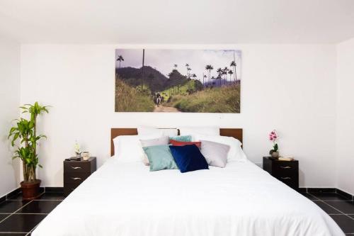 Un dormitorio con una cama blanca y una pintura en la pared en Cozy 4 Bedroom Home with Jacuzzi and Outside Deck, en Armenia